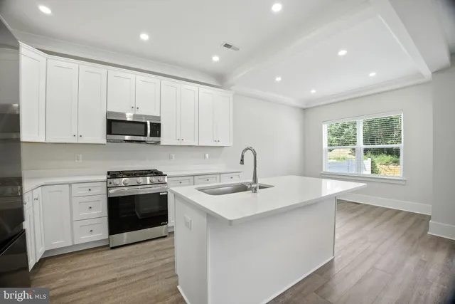 a kitchen with stainless steel appliances granite countertop a sink a stove and a wooden floors