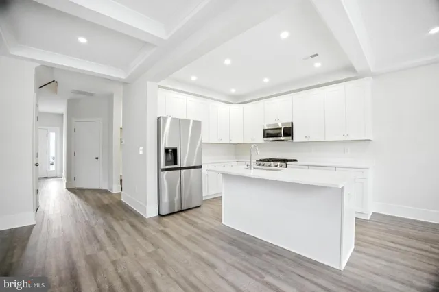 a kitchen with a refrigerator a stove top oven and wooden floor