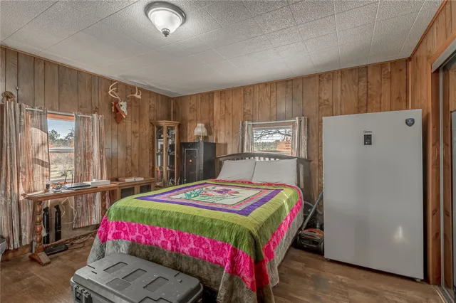 a bedroom with a bed a dresser and a large window