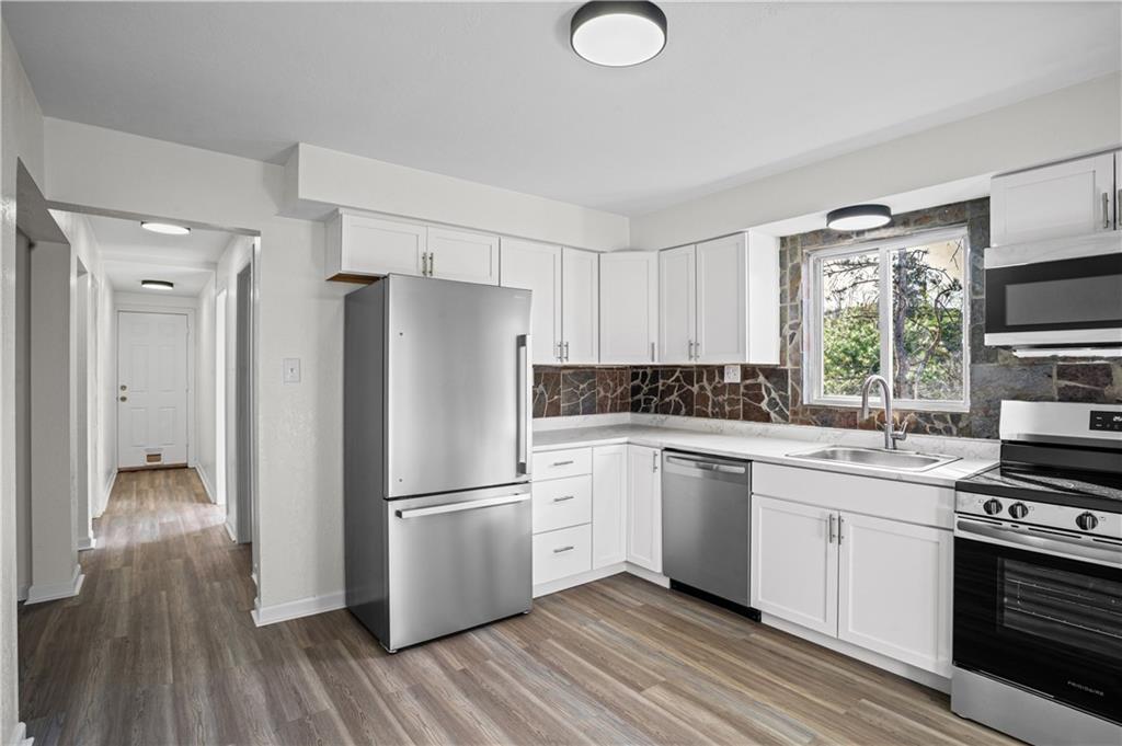 1305 Main Street Bridgeville, PA 15017 - Photo 5 of 50 a kitchen with a refrigerator a sink dishwasher a stove and white cabinets with wooden floor