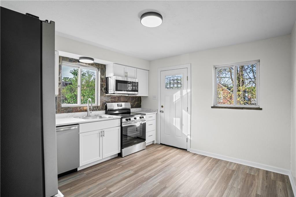 1305 Main Street Bridgeville, PA 15017 - Photo 6 of 50 a kitchen with stainless steel appliances a stove top oven a sink a refrigerator a window and cabinets