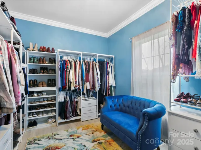 a walk in closet with clothes and shoes