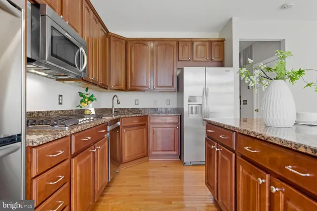 a kitchen with stainless steel appliances granite countertop a refrigerator a stove top oven and a sink