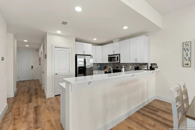 a view of a kitchen with stainless steel appliances refrigerator stove microwave and cabinets