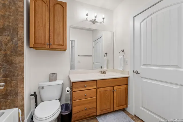 a bathroom with a granite countertop toilet sink and mirror