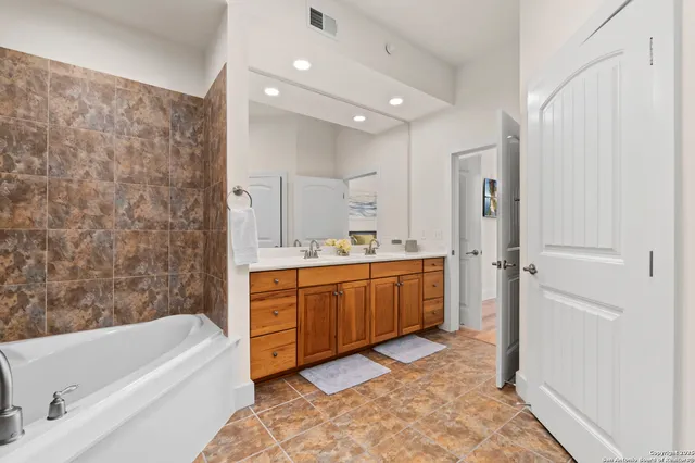 a bathroom with a tub a sink and a large mirror