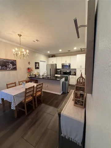 a kitchen with stainless steel appliances kitchen island granite countertop a table chairs and a refrigerator