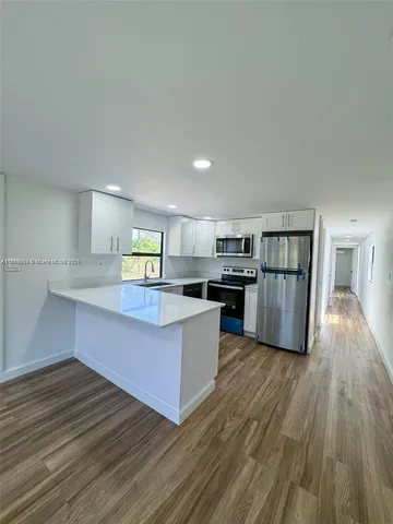a kitchen with stainless steel appliances wooden floors and wooden cabinets