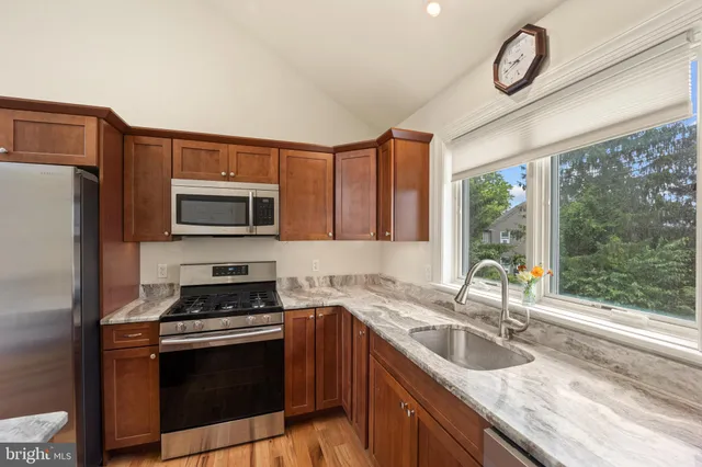 a kitchen with stainless steel appliances granite countertop a sink a stove a washer and dryer
