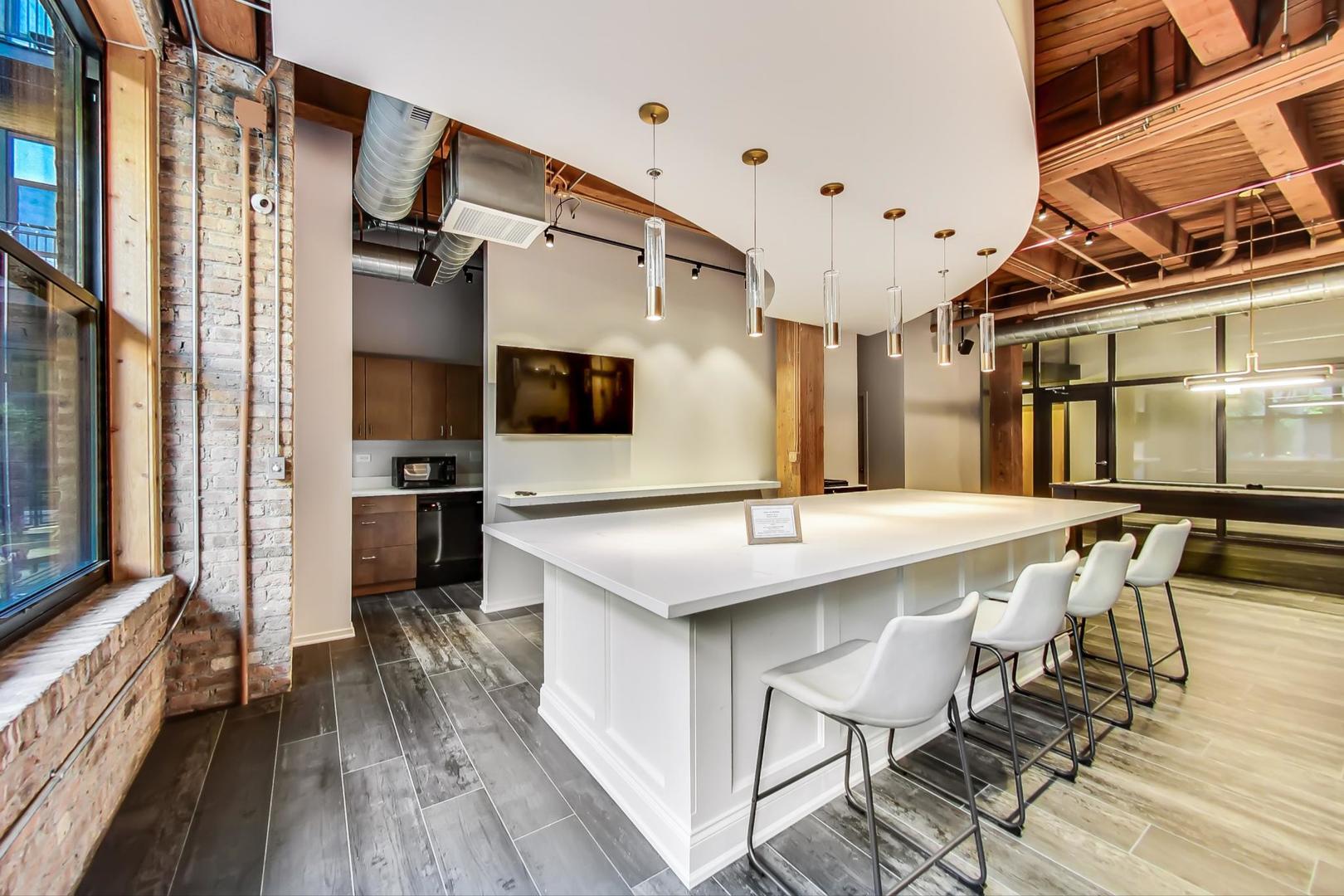 1040 West Adams Street, Unit 220 Chicago, IL 60607 - Photo 21 of 27 a kitchen with kitchen island a sink table and chairs