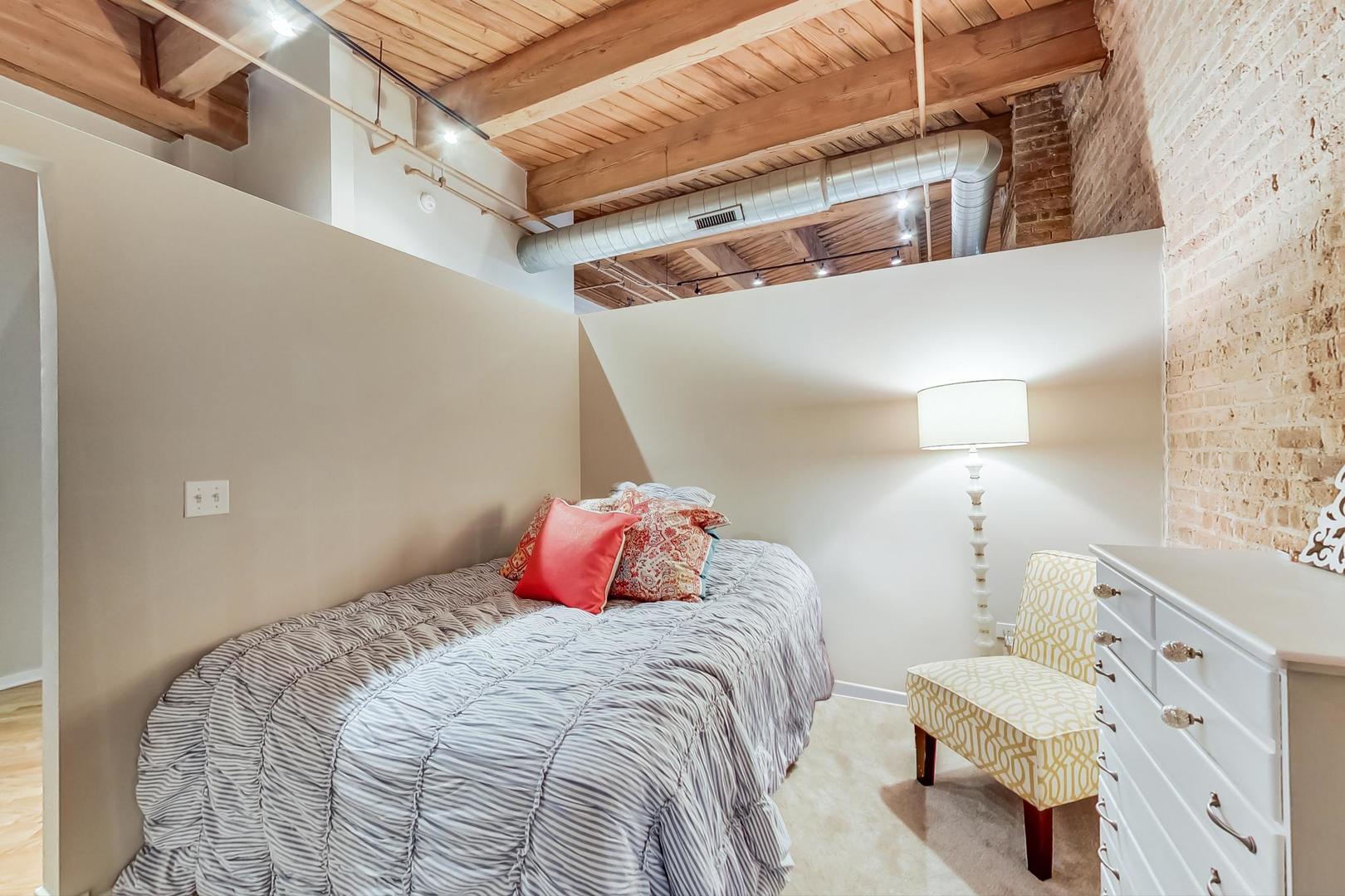 1040 West Adams Street, Unit 220 Chicago, IL 60607 - Photo 9 of 27 a bedroom with a bed and a mirror