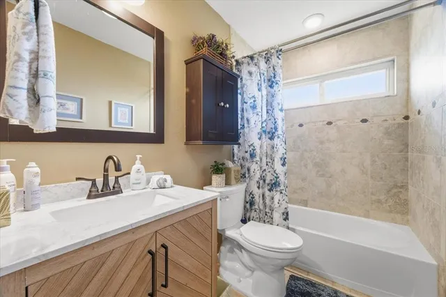 a bathroom with a sink a toilet a mirror a bathtub and shower