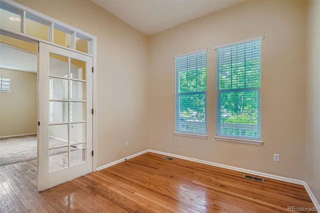 a view of an empty room with wooden floor and a window