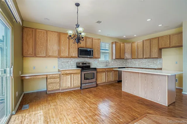 a kitchen with kitchen island granite countertop a sink cabinets and stainless steel appliances