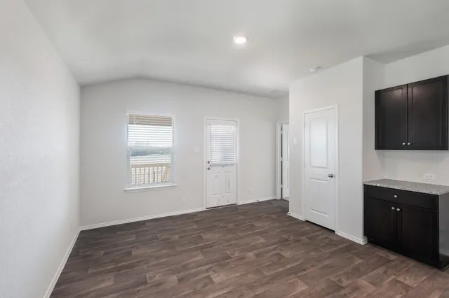 a view of an empty room with a window and a kitchen
