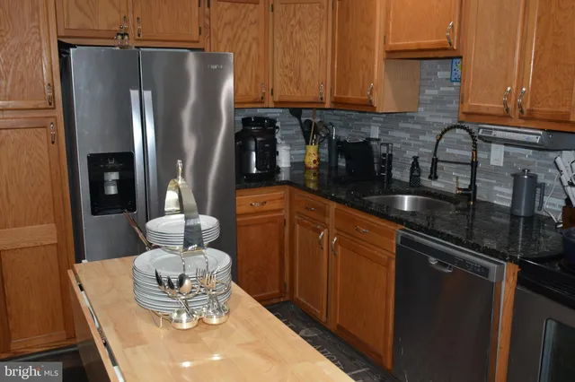 a kitchen with stainless steel appliances granite countertop a refrigerator a sink a stove and chairs