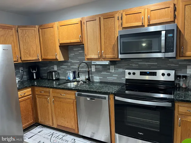 a kitchen with stainless steel appliances a stove a microwave a sink and cabinets
