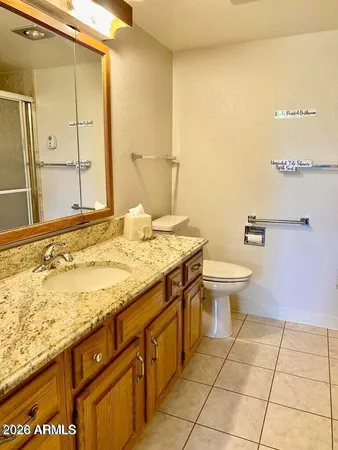 a bathroom with a granite countertop sink a toilet and a mirror