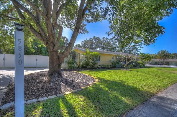 a backyard of a house with table and chairs under an umbrella
