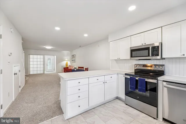 a kitchen with granite countertop white cabinets stainless steel appliances and a window