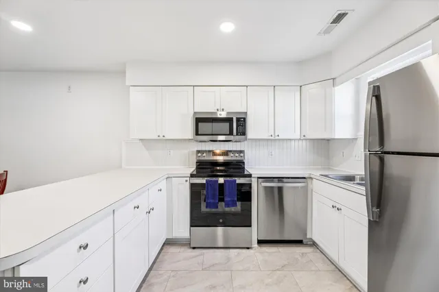 a kitchen with granite countertop white cabinets and stainless steel appliances