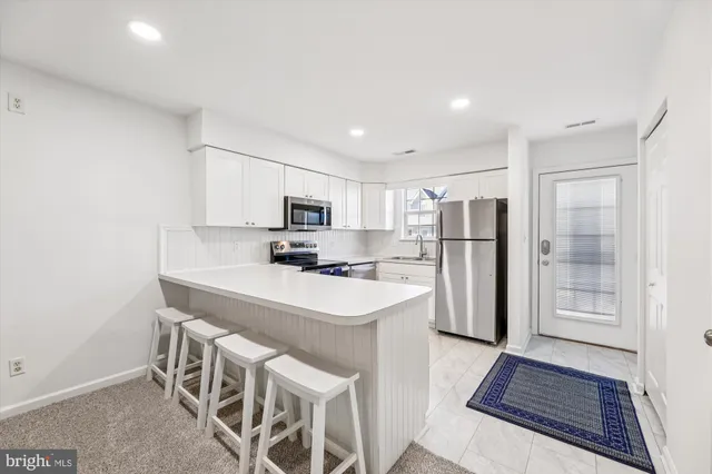 a kitchen with stainless steel appliances a refrigerator a stove a sink and white cabinets