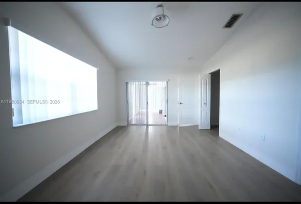 a view of an empty room with wooden floor and a window