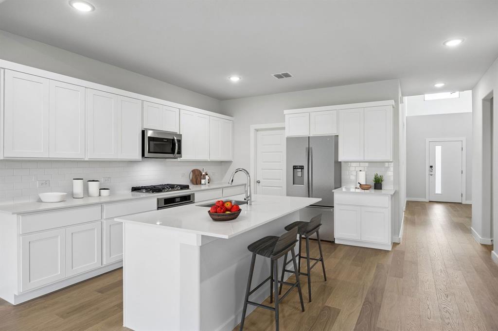 1460 Companero Street Haslet, TX 76052 - Photo 6 of 35 a kitchen with white cabinets and stainless steel appliances