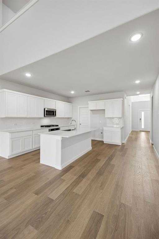 1460 Companero Street Haslet, TX 76052 - Photo 9 of 35 a large kitchen with kitchen island a stove a refrigerator a white cabinets and wooden floor
