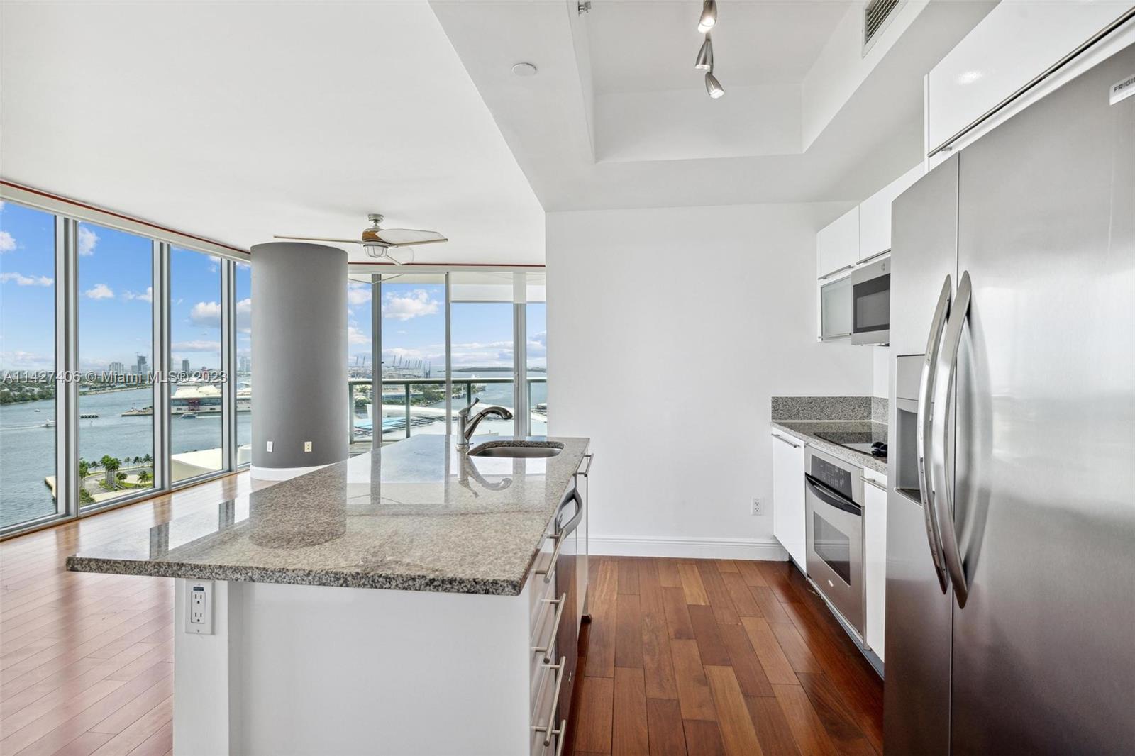 888 Biscayne Boulevard, Unit 2208 Miami, FL 33132 - Photo 3 of 20 a kitchen with granite countertop a refrigerator a sink a stove and oven with wooden floor
