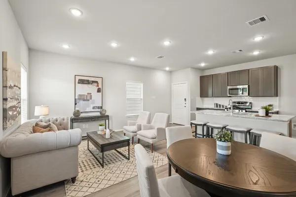 a living room with stainless steel appliances furniture a dining table and chairs