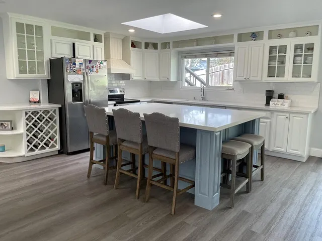 a kitchen with stainless steel appliances granite countertop a table chairs sink refrigerator and cabinets