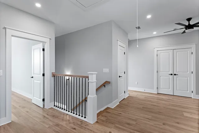 a view of a hallway with wooden floor and closet area