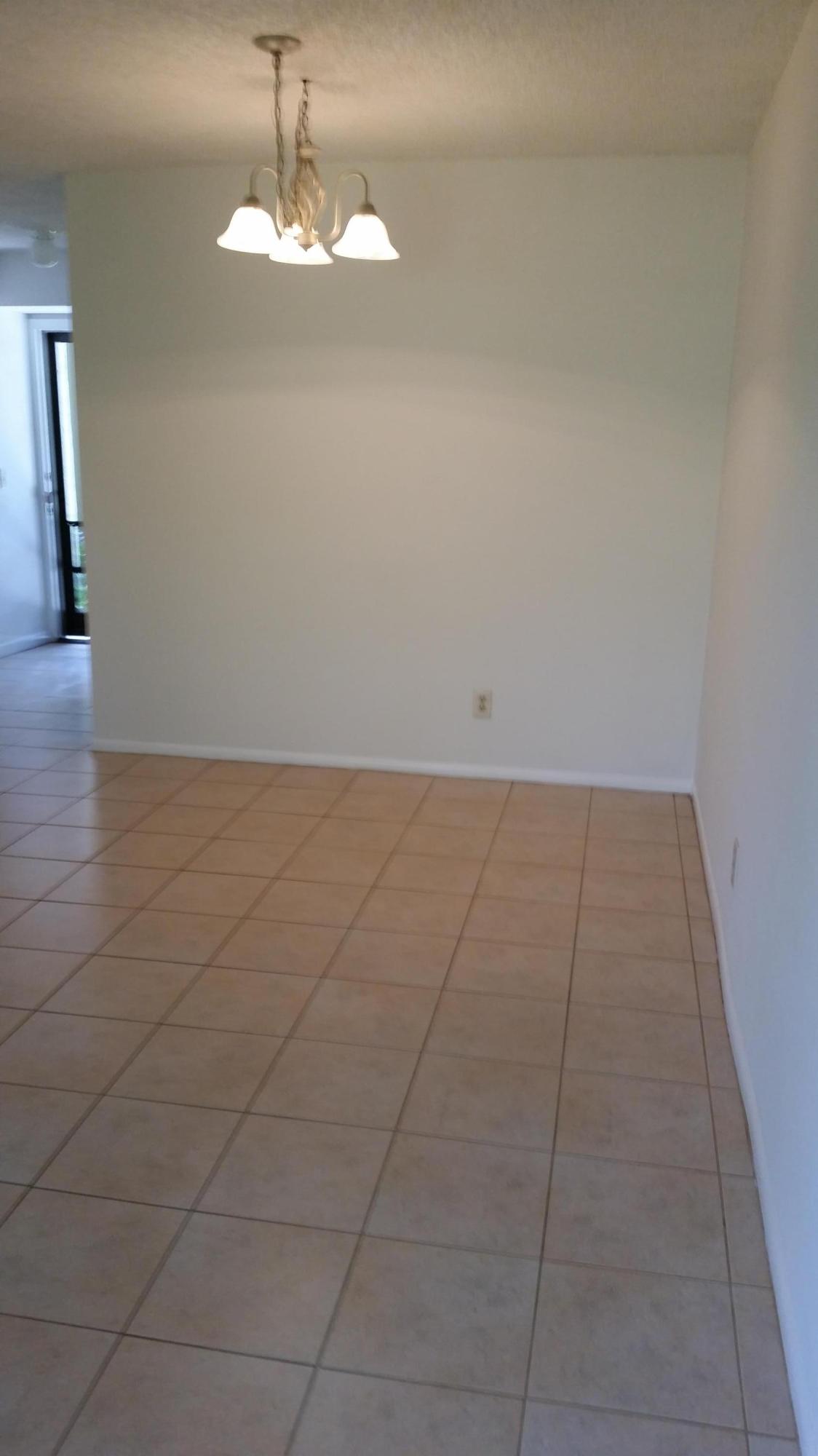 800 Northwest Fork Road, Unit 71 Stuart, FL 34994 - Photo 10 of 23 an empty room with wooden floor and a chandelier