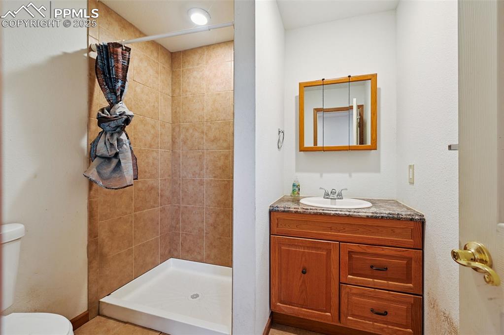1220 Choate Lane Yoder, CO 80864 - Photo 26 of 47 a bathroom with a shower sink vanity and mirror