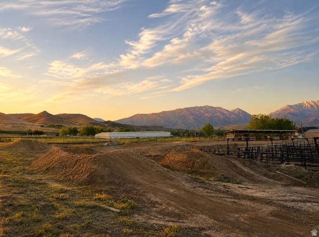 115 East 1600th Street North Santaquin, UT 84655 - Photo 52 of 52 Expansive outdoor property featuring multiple dirt mounds, a partially visible white agricultural building, and a brown open-sided structure with a dark roof