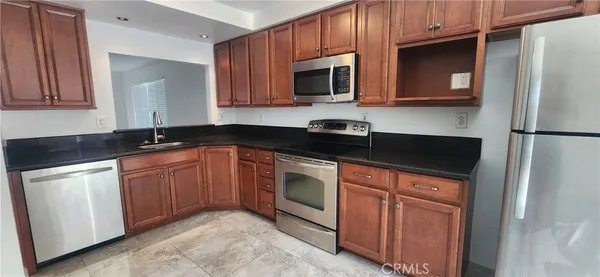a kitchen with granite countertop a refrigerator stove and microwave