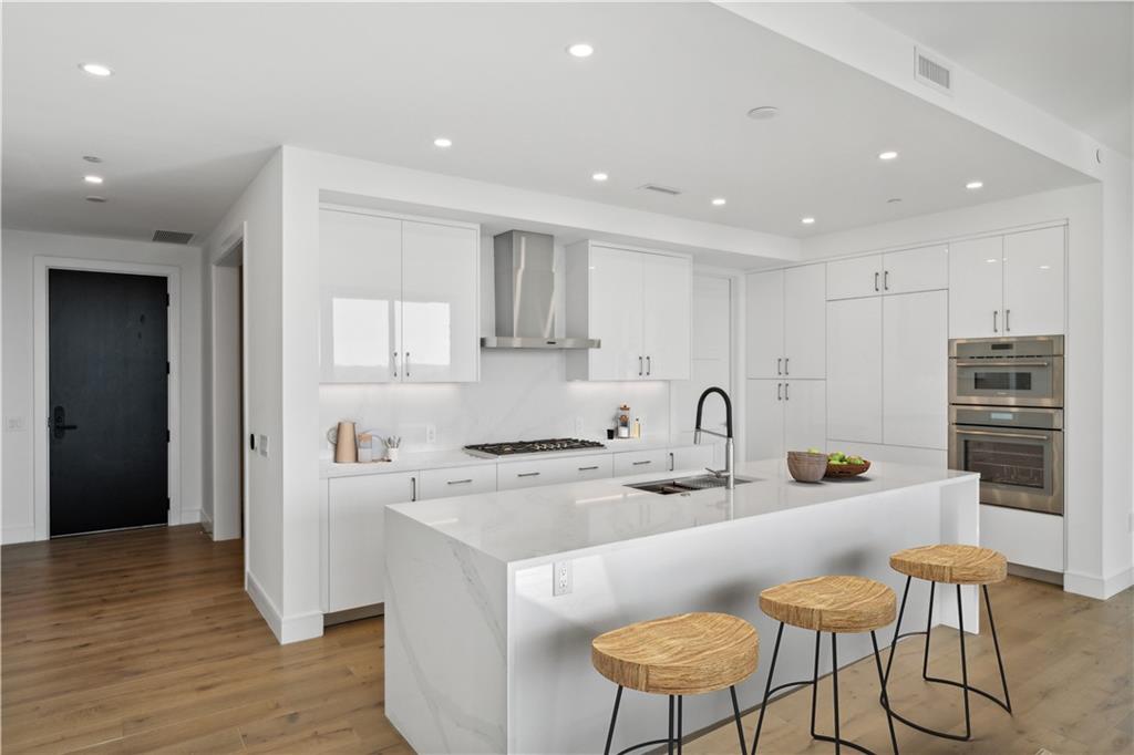 2425 Peachtree Street Northeast, Unit 1106 Atlanta, GA 30305 - Photo 6 of 43 a kitchen with stainless steel appliances a sink a stove a refrigerator cabinets and wooden floor