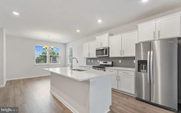 a kitchen with stainless steel appliances a refrigerator a stove a sink cabinets and wooden floor