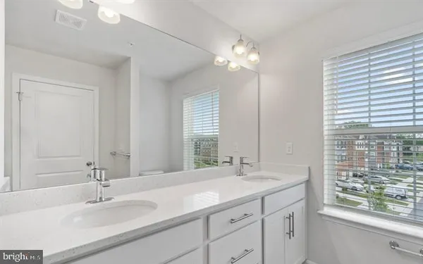 a bathroom with double vanity and a mirror