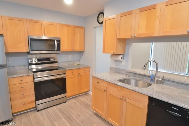 a kitchen with granite countertop a sink cabinets and stainless steel appliances