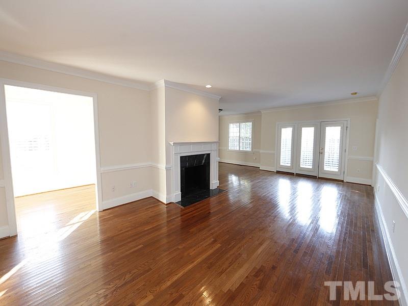 2301 Elmsford Way Raleigh, NC 27608 - Photo 4 of 25 an empty room with wooden floor and fireplace