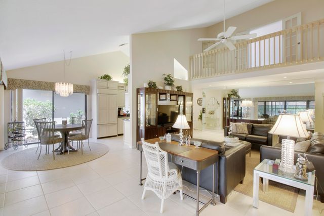 a living room with couches a fireplace and dining table with wooden floor