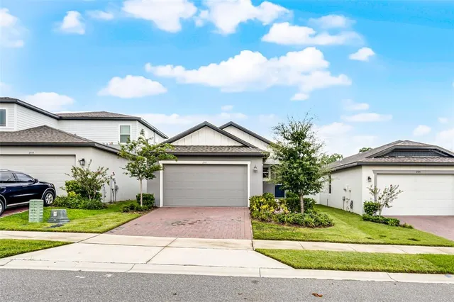 a front view of a house with a yard and potted plants