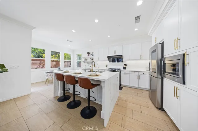 a kitchen with stainless steel appliances kitchen island granite countertop a table chairs sink and cabinets