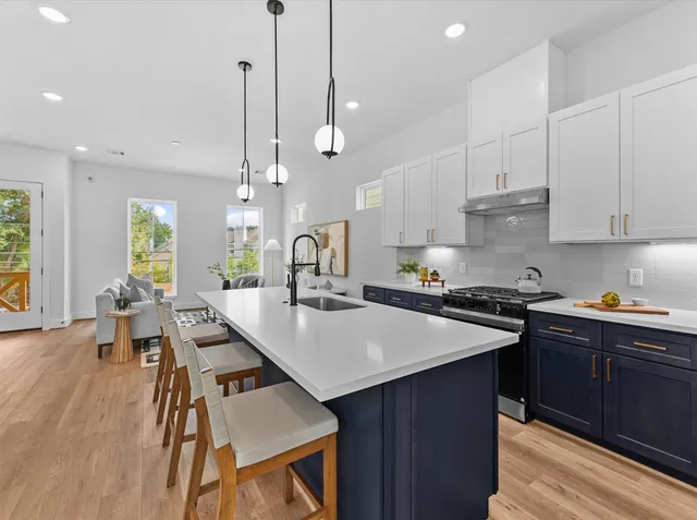 a kitchen with stainless steel appliances granite countertop a stove a sink a refrigerator a stove a dining table and chairs with wooden floor