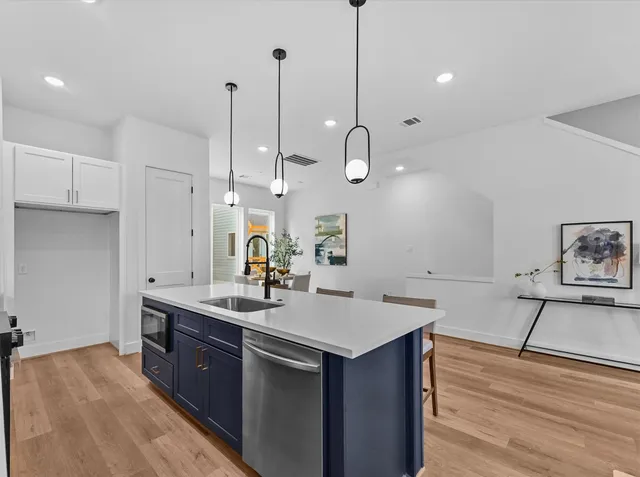 a kitchen with a sink appliances and a wooden floor