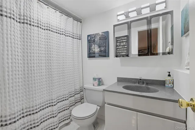a bathroom with a granite countertop sink mirror vanity and toilet