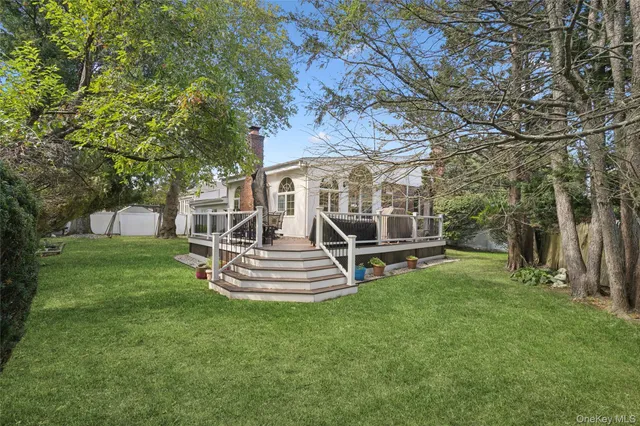 a view of a house with a yard deck and a large tree