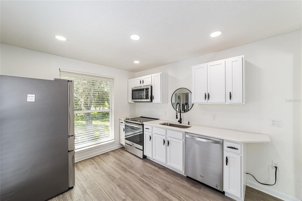 10399 Northeast 218th Lane Road Fort McCoy, FL 32134 - Photo 45 of 68 a kitchen with stainless steel appliances granite countertop a sink and wooden cabinets